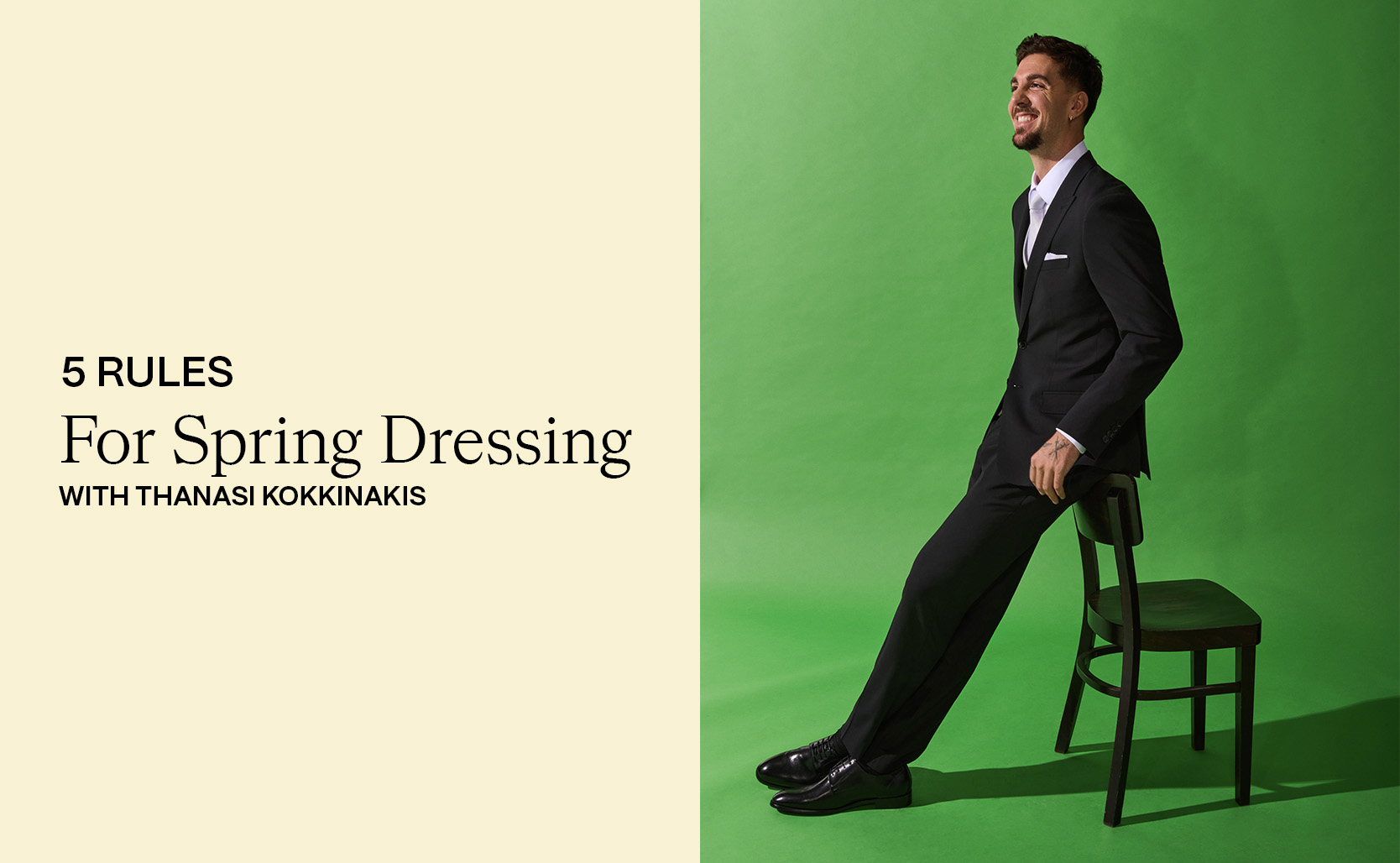 Thanasi Kokkinakis sitting on a chair wearing a tailored black suit and white shirt against a green backdrop. Text beside him reads “5 Rules for Spring Dressing with Thanasi Kokkinakis.”
